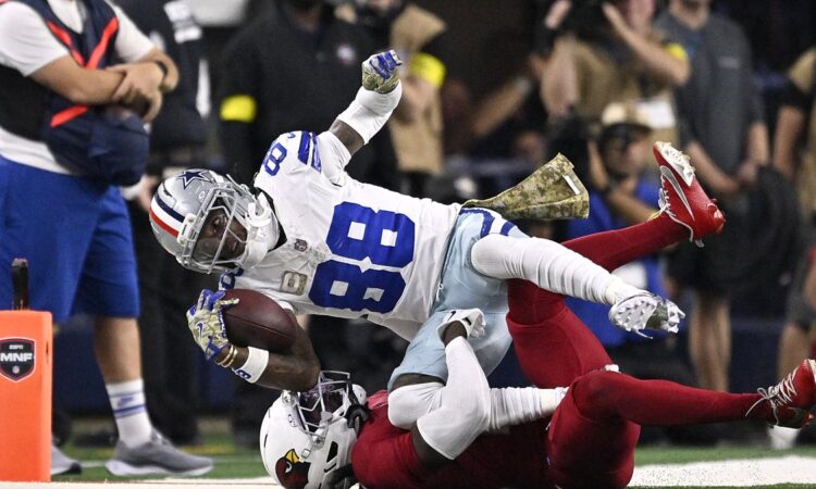 Dallas Cowboys wide receiver CeeDee Lamb reaches out with the ball as Arizona Cardinals cornerback Will Johnson tackles him.
