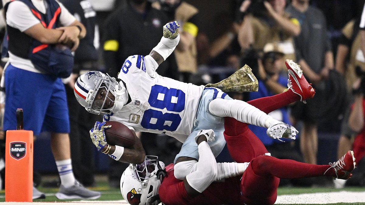 Dallas Cowboys wide receiver CeeDee Lamb reaches out with the ball as Arizona Cardinals cornerback Will Johnson tackles him.