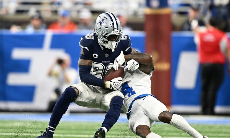 Dallas Cowboys wide receiver CeeDee Lamb secures a catch as Detroit Lions cornerback D.J. Reed wraps him up.