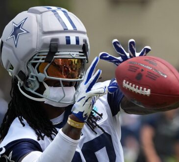 Cowboys receiver CeeDee Lamb reaches out to catch a ball while wearing a Guardian helmet cap at training camp