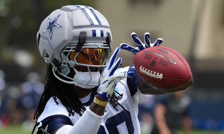 Cowboys receiver CeeDee Lamb reaches out to catch a ball while wearing a Guardian helmet cap at training camp