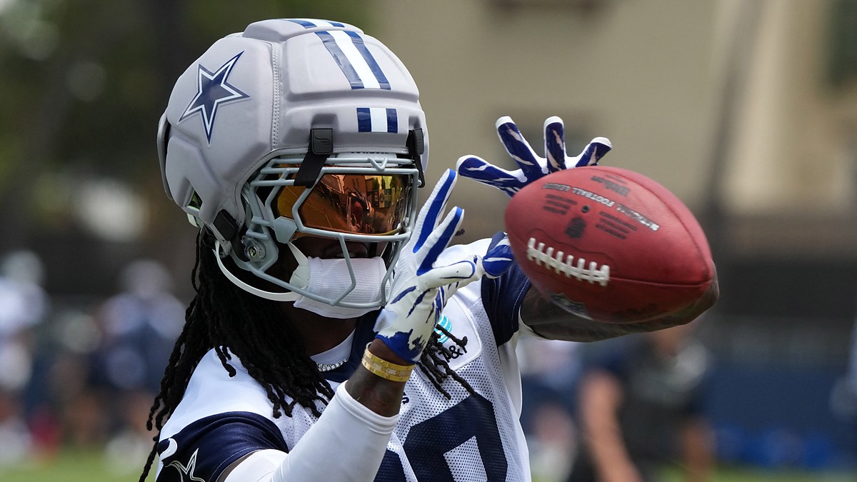 Cowboys receiver CeeDee Lamb reaches out to catch a ball while wearing a Guardian helmet cap at training camp