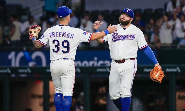 Texas Rangers third baseman Cody Freeman and first baseman Jake Burger slap hands on the field after a win.