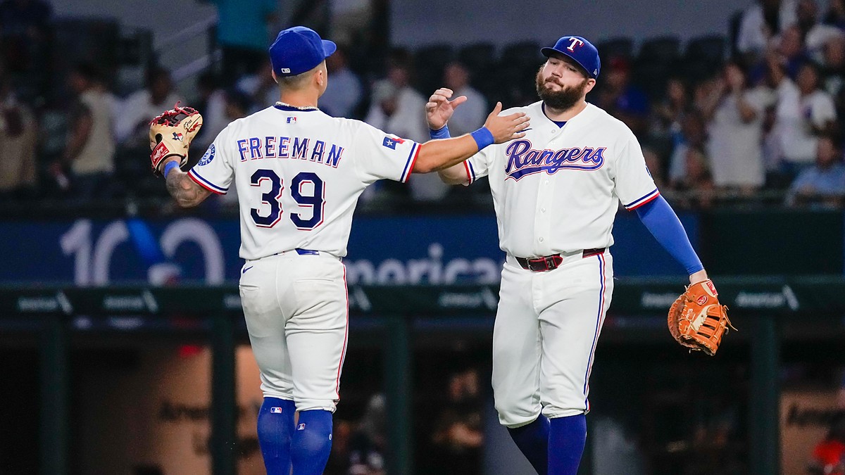 Texas Rangers third baseman Cody Freeman and first baseman Jake Burger slap hands on the field after a win.