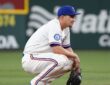 Texas Rangers shortstop Corey Seager crouches on the infield dirt with his glove resting on the ground.