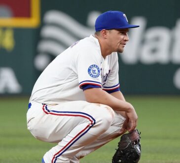 Texas Rangers shortstop Corey Seager crouches on the infield dirt with his glove resting on the ground.