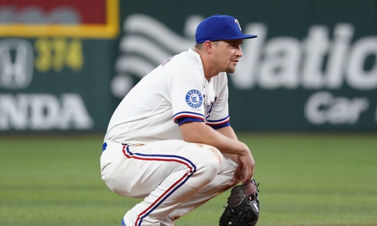 Texas Rangers shortstop Corey Seager crouches on the infield dirt with his glove resting on the ground.