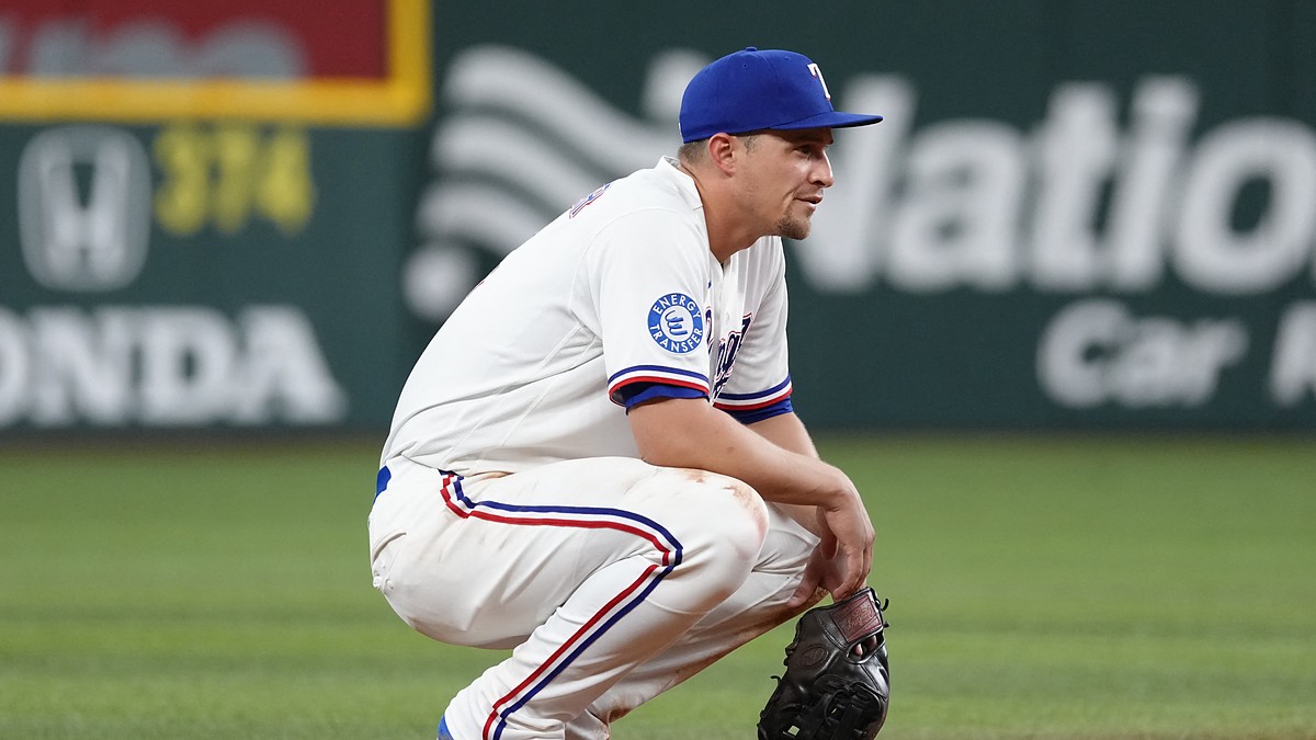 Texas Rangers shortstop Corey Seager crouches on the infield dirt with his glove resting on the ground.