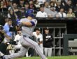 Texas Rangers shortstop Corey Seager follows through on a swing in a road grey uniform at Rate Field.