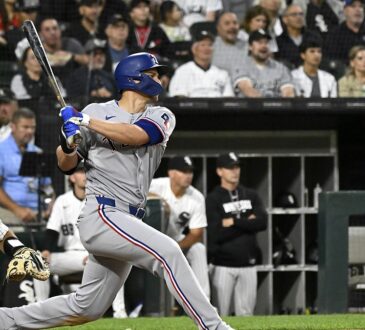 Texas Rangers shortstop Corey Seager follows through on a swing in a road grey uniform at Rate Field.