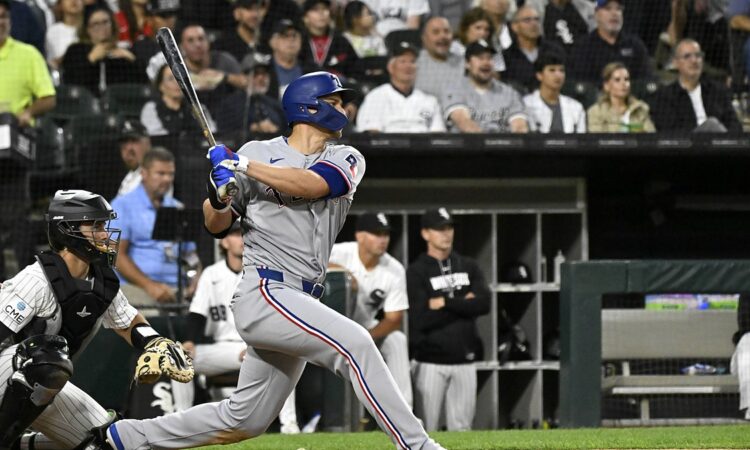 Texas Rangers shortstop Corey Seager follows through on a swing in a road grey uniform at Rate Field.
