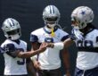 Cowboys receivers KaVontae Turpin, George Pickens, and CeeDee Lamb clasp hands in helmets at training camp
