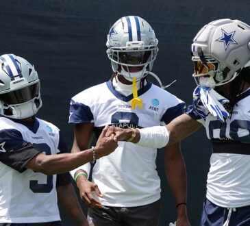 Cowboys receivers KaVontae Turpin, George Pickens, and CeeDee Lamb clasp hands in helmets at training camp
