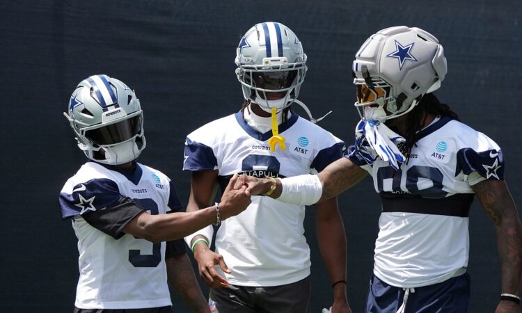 Cowboys receivers KaVontae Turpin, George Pickens, and CeeDee Lamb clasp hands in helmets at training camp