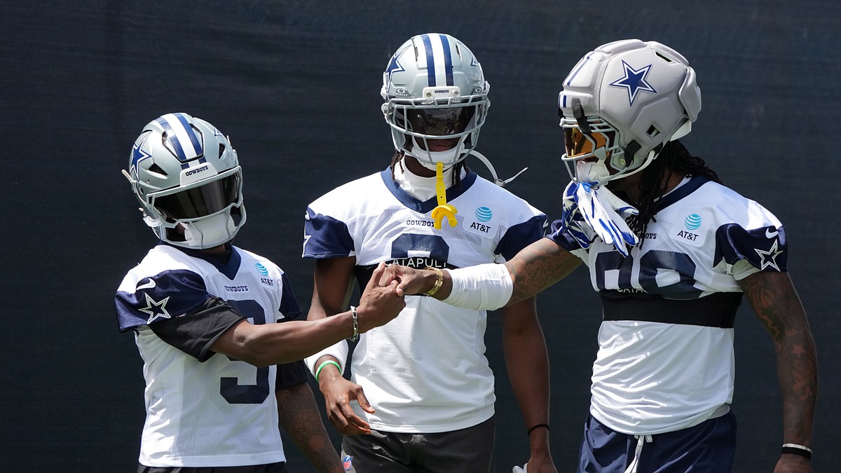 Cowboys receivers KaVontae Turpin, George Pickens, and CeeDee Lamb clasp hands in helmets at training camp