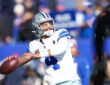 Dallas Cowboys quarterback Dak Prescott cocks his arm to throw during warmups in a white No. 4 jersey.