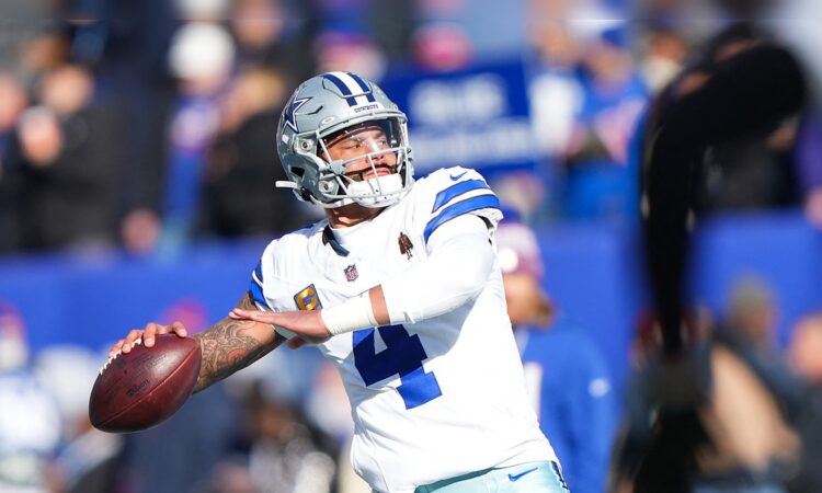 Dallas Cowboys quarterback Dak Prescott cocks his arm to throw during warmups in a white No. 4 jersey.