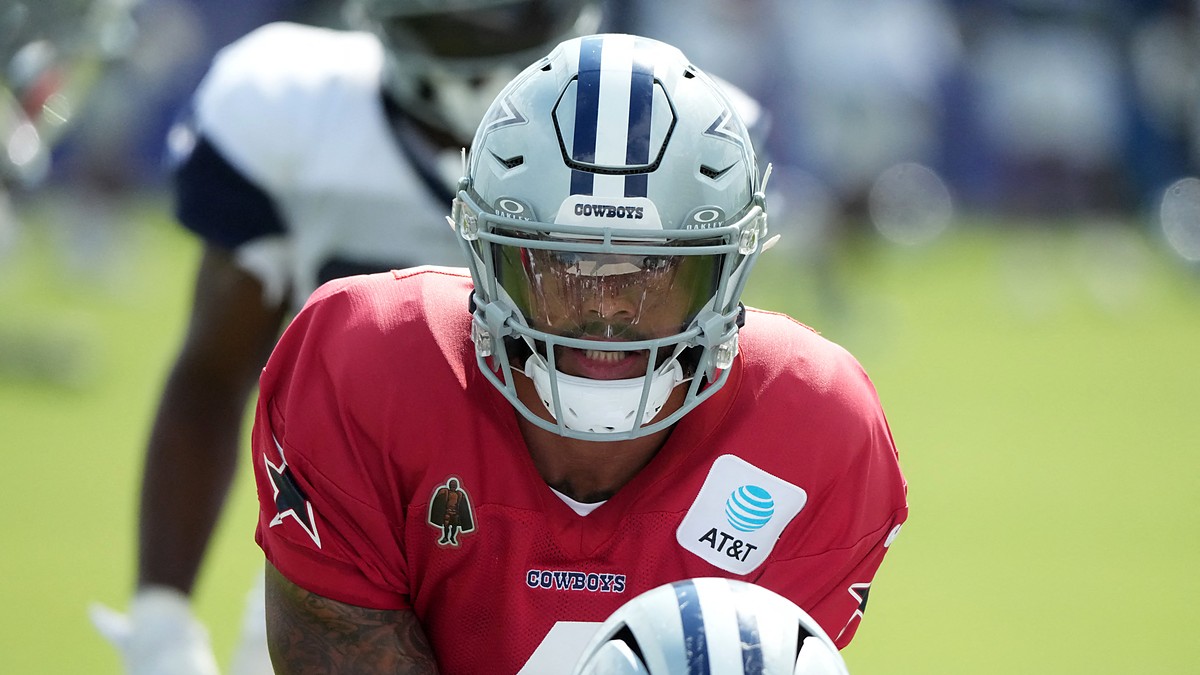 Dallas Cowboys quarterback Dak Prescott leans under center in a red non-contact jersey during joint practice.