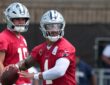 Dallas Cowboys quarterback Dak Prescott holds the football during a drill as quarterback Sam Howell looks on.