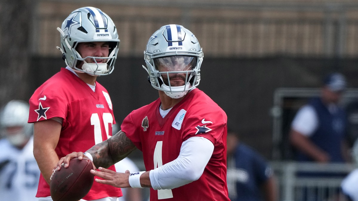 Dallas Cowboys quarterback Dak Prescott holds the football during a drill as quarterback Sam Howell looks on.