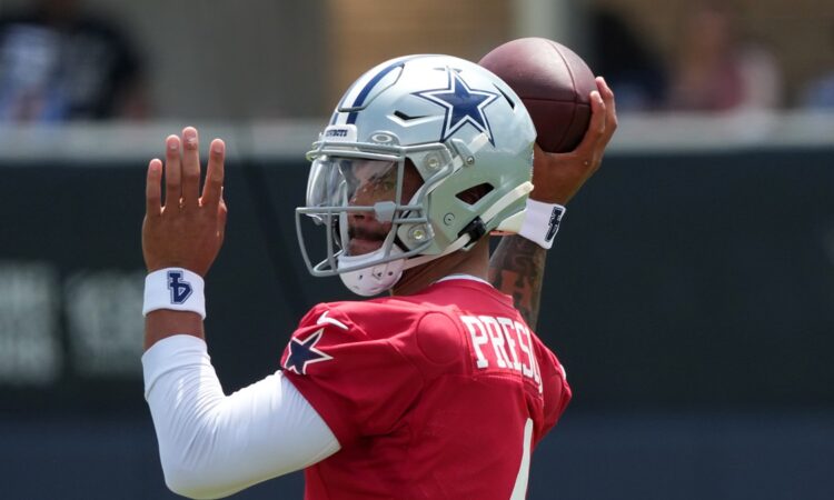 Dallas Cowboys quarterback Dak Prescott cocks the football behind his helmet in his throwing motion.