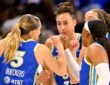 Dallas Wings guard Paige Bueckers huddles with teammates in blue uniforms at midcourt before tipoff.