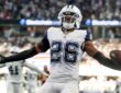 Dallas Cowboys cornerback DaRon Bland spreads his arms with the ball in one hand after an interception return.