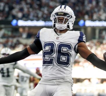 Dallas Cowboys cornerback DaRon Bland spreads his arms with the ball in one hand after an interception return.