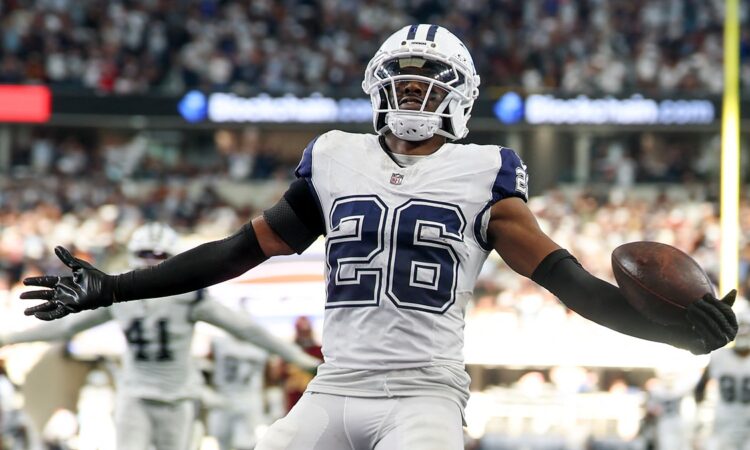 Dallas Cowboys cornerback DaRon Bland spreads his arms with the ball in one hand after an interception return.