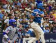 Milwaukee Brewers third baseman David Hamilton follows through on an RBI single as Texas Rangers catcher Danny Jansen watches from behind the plate.