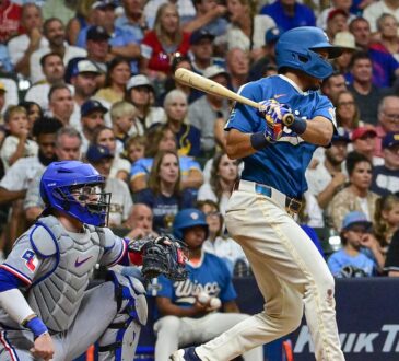Milwaukee Brewers third baseman David Hamilton follows through on an RBI single as Texas Rangers catcher Danny Jansen watches from behind the plate.