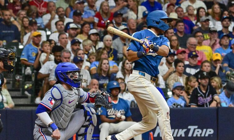 Milwaukee Brewers third baseman David Hamilton follows through on an RBI single as Texas Rangers catcher Danny Jansen watches from behind the plate.