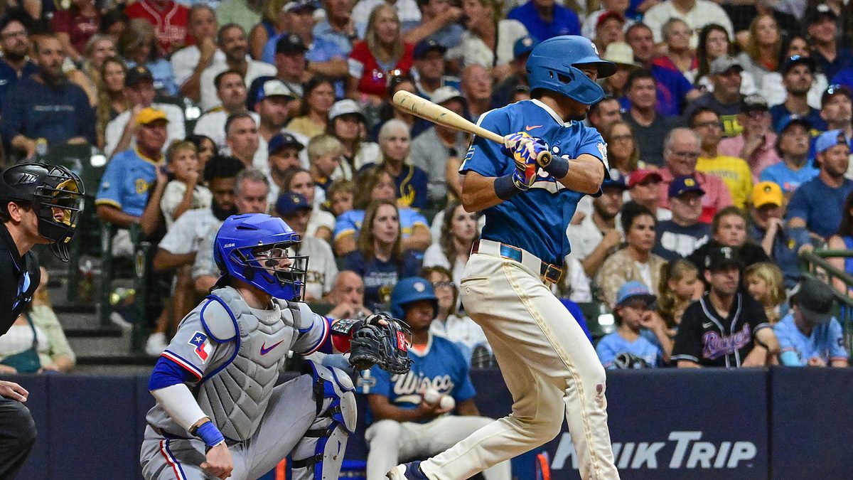 Milwaukee Brewers third baseman David Hamilton follows through on an RBI single as Texas Rangers catcher Danny Jansen watches from behind the plate.