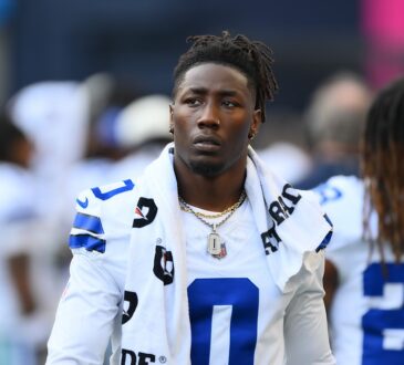 Dallas Cowboys linebacker DeMarvion Overshown stands on the sideline in uniform with a towel around his neck.