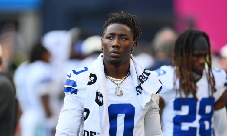 Dallas Cowboys linebacker DeMarvion Overshown stands on the sideline in uniform with a towel around his neck.