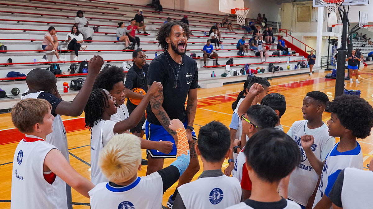 Dallas Mavericks center Dereck Lively II fires up a huddle of young campers at a Mavs Academy hoop camp.