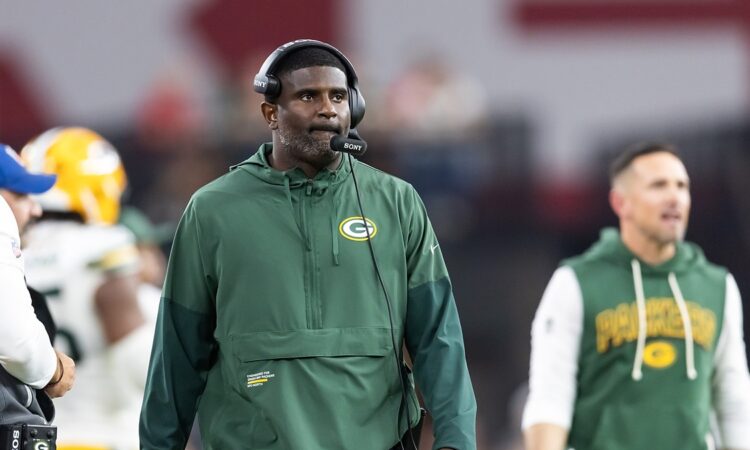 Green Bay Packers passing game coordinator Derrick Ansley watches from the sideline wearing a headset.