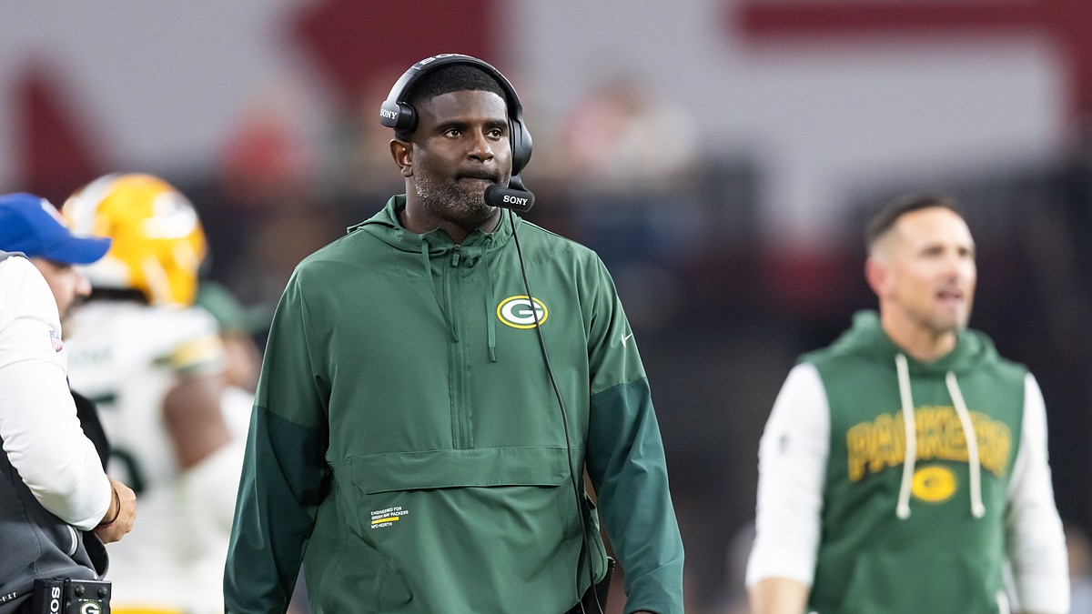 Green Bay Packers passing game coordinator Derrick Ansley watches from the sideline wearing a headset.
