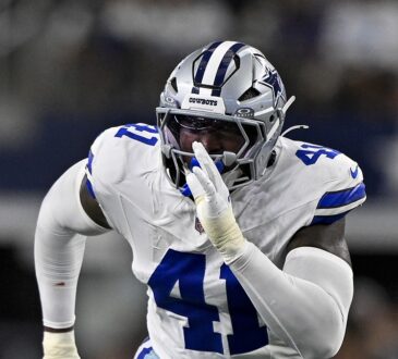 Dallas Cowboys defensive end Donovan Ezeiruaku fires off the line with his hand up in a white No. 41 jersey.
