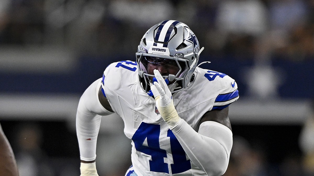 Dallas Cowboys defensive end Donovan Ezeiruaku fires off the line with his hand up in a white No. 41 jersey.