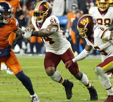 Denver Broncos tight end Evan Engram carries the ball as Commanders linebacker Bobby Wagner reaches for him from behind.