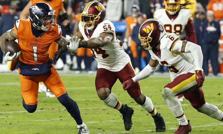 Denver Broncos tight end Evan Engram carries the ball as Commanders linebacker Bobby Wagner reaches for him from behind.