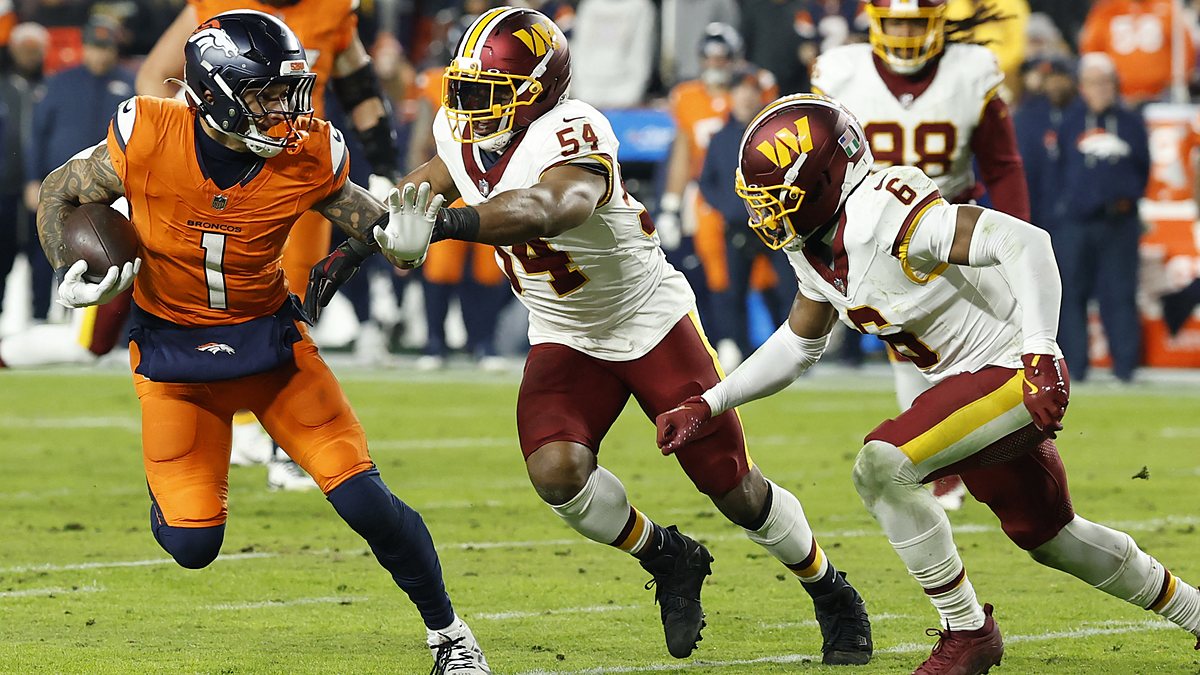 Denver Broncos tight end Evan Engram carries the ball as Commanders linebacker Bobby Wagner reaches for him from behind.