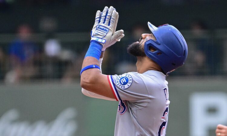 Texas Rangers batter Ezequiel Durán raises his hands and looks skyward after reaching base at American Family Field.