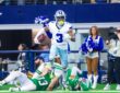 Dallas Cowboys wide receiver George Pickens carries the ball past two fallen Eagles defenders along the sideline.