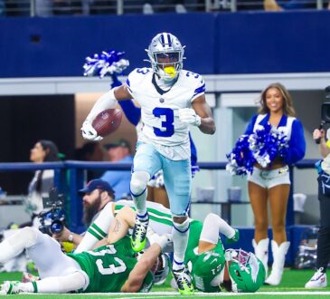 Dallas Cowboys wide receiver George Pickens carries the ball past two fallen Eagles defenders along the sideline.