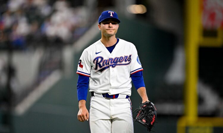 Texas Rangers starting pitcher Jack Leiter walks off the field with his glove after finishing an inning.