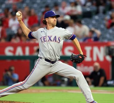 Texas Rangers pitcher Jacob deGrom strides toward the plate in road grays, ball hidden behind his hip.