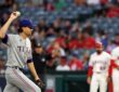 Rangers pitcher Jacob deGrom holds up a new ball on the mound as an Angels runner stands at first