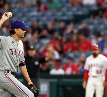 Rangers pitcher Jacob deGrom holds up a new ball on the mound as an Angels runner stands at first